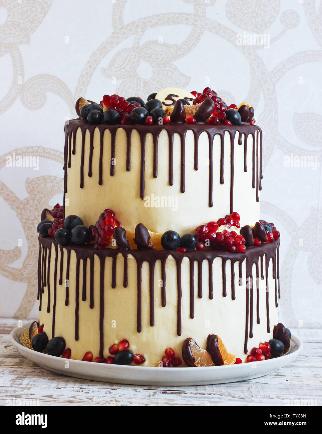 Festive two-tier cake with fruit with streaks of chocolate on a ...