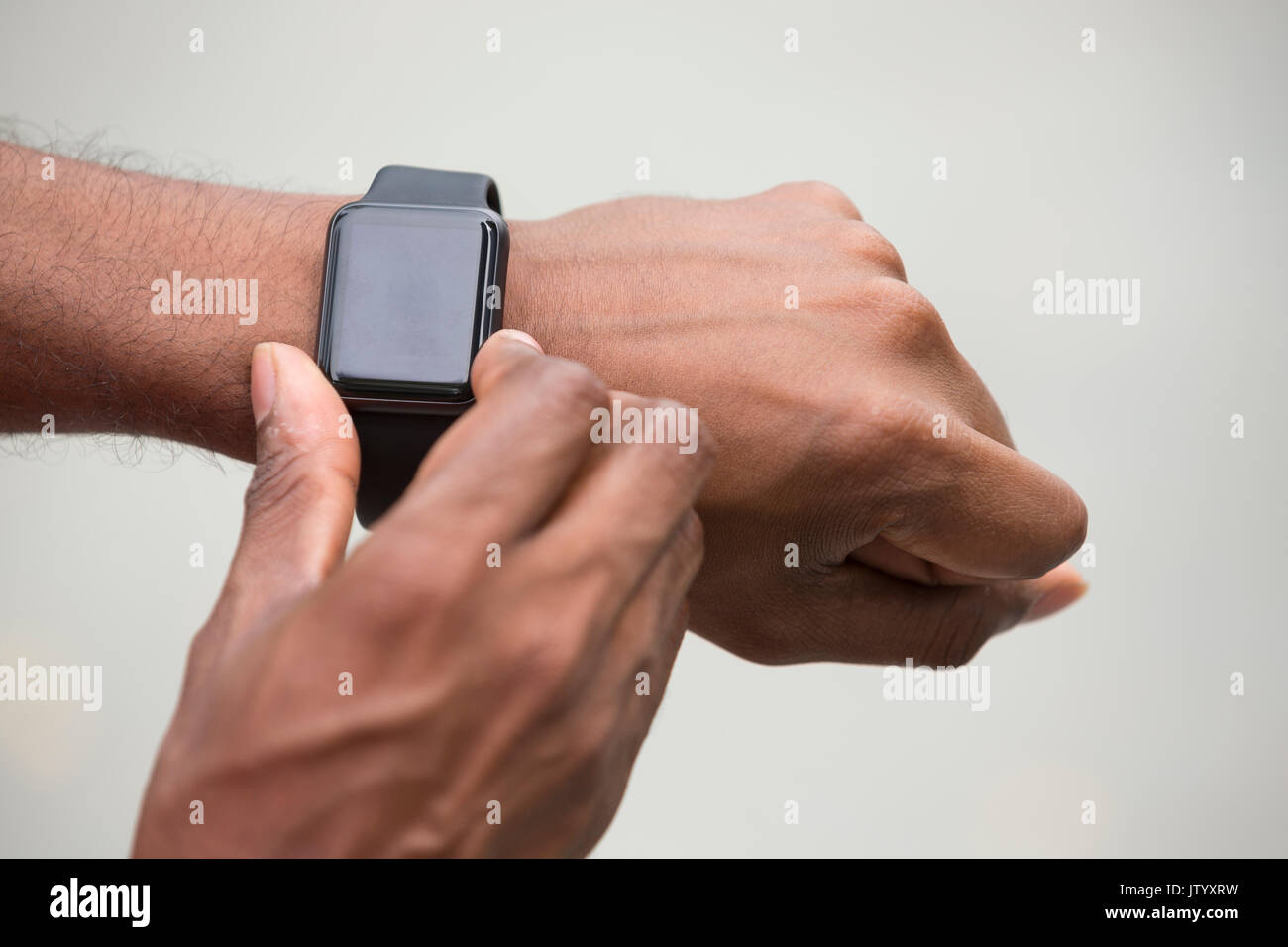 Close up of an Indian man looking at his smartwatch heart rate monitor. Asian man using a smart watch. Stock Photo