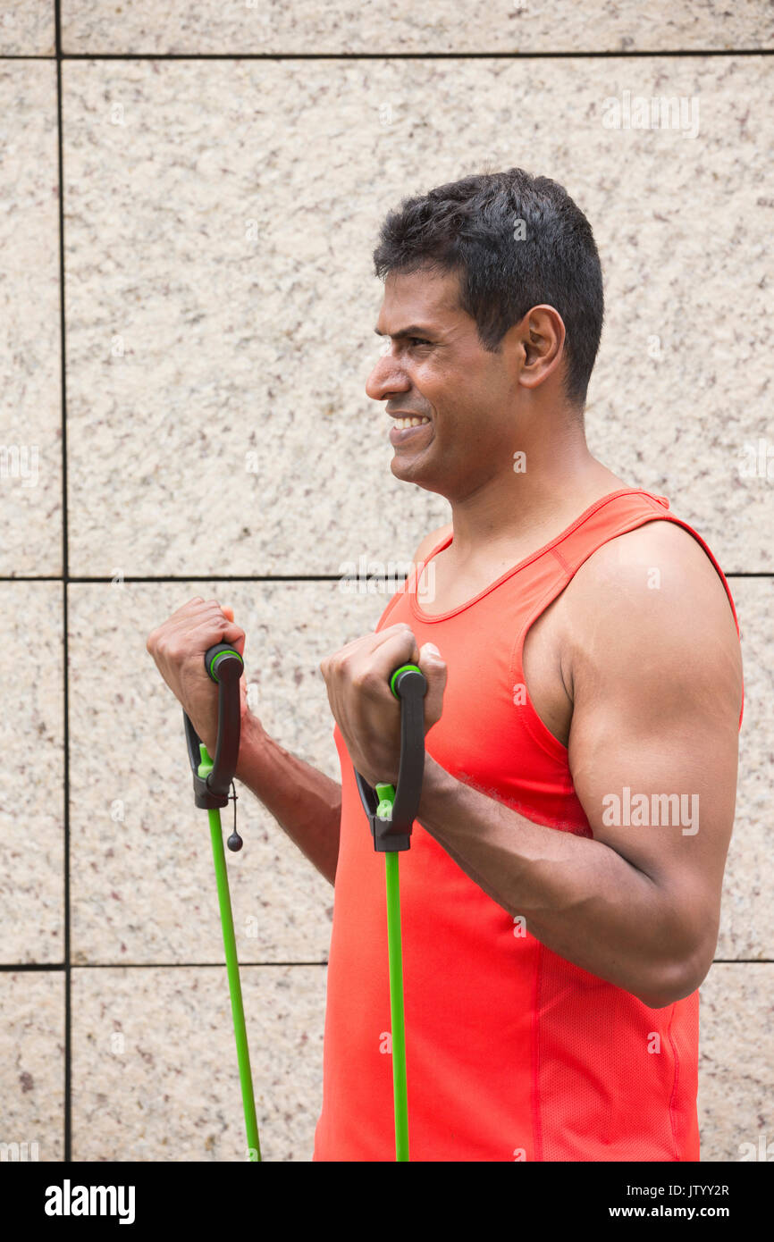 Portrait of an athletic Indian man using stretch bands outdoors in urban setting. Stock Photo
