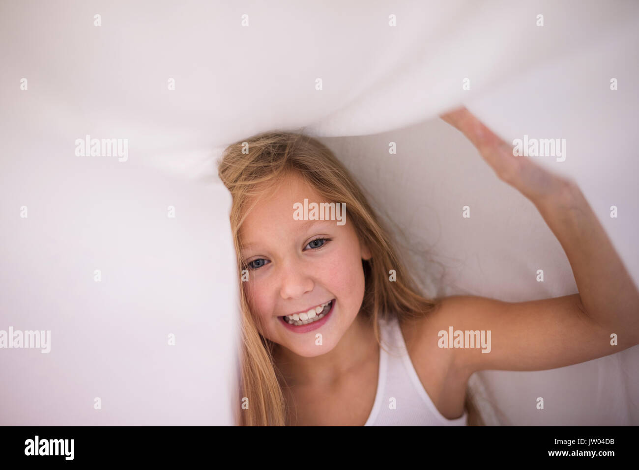 Little girl hiding under the sheet Stock Photo