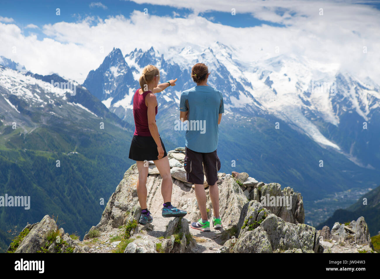 Two runners are standing on top of a mountain, overlooking the Chamonix valley and Mont Blanc range. This region in the French Alps is popular for trail running or sky running. Stock Photo