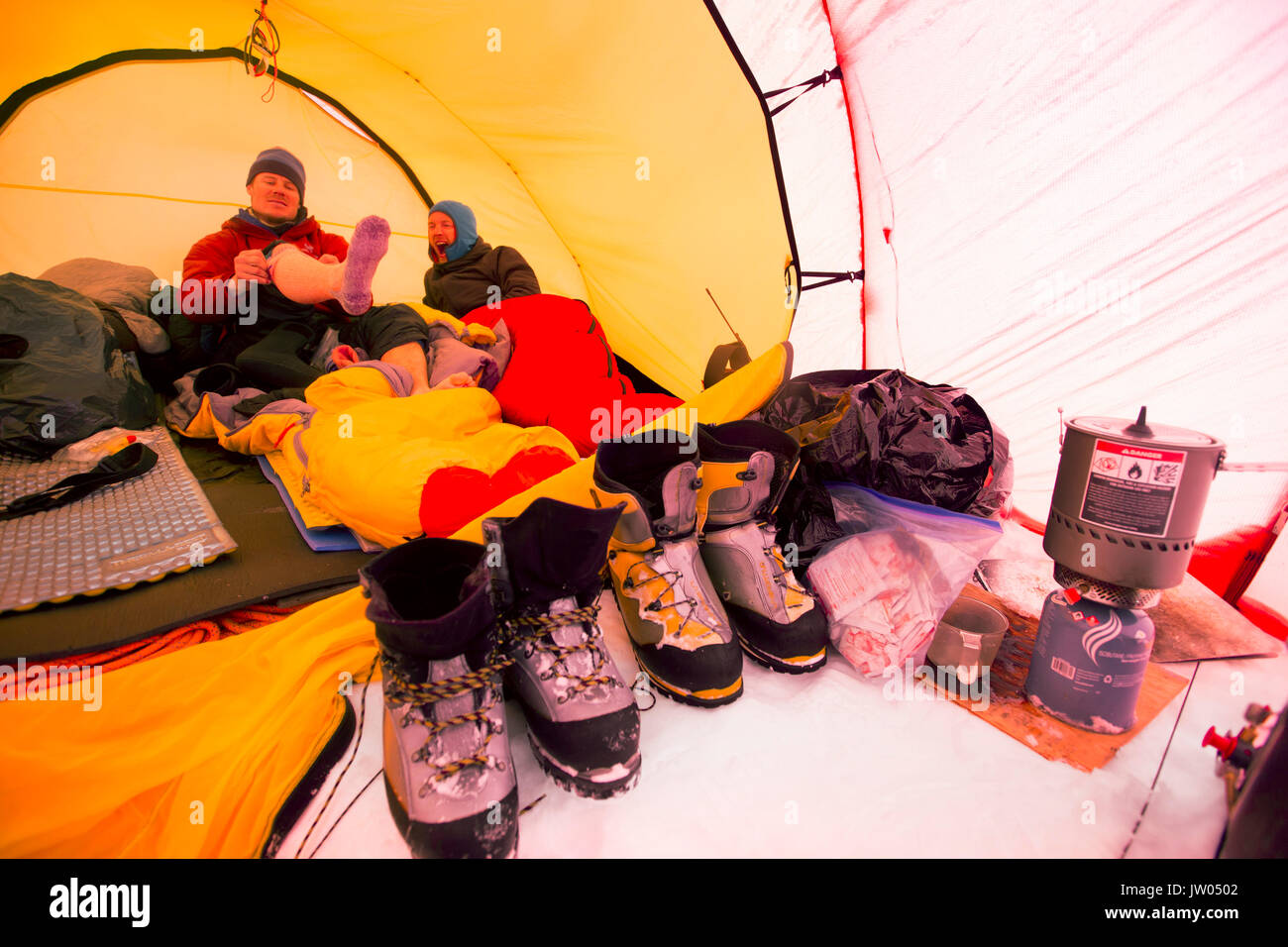 Two mountaineers are laying inside a tent at High Camp on Denali in Alaska. Early morning they are going for a summit push to the highest mountain of Northern America. Stock Photo