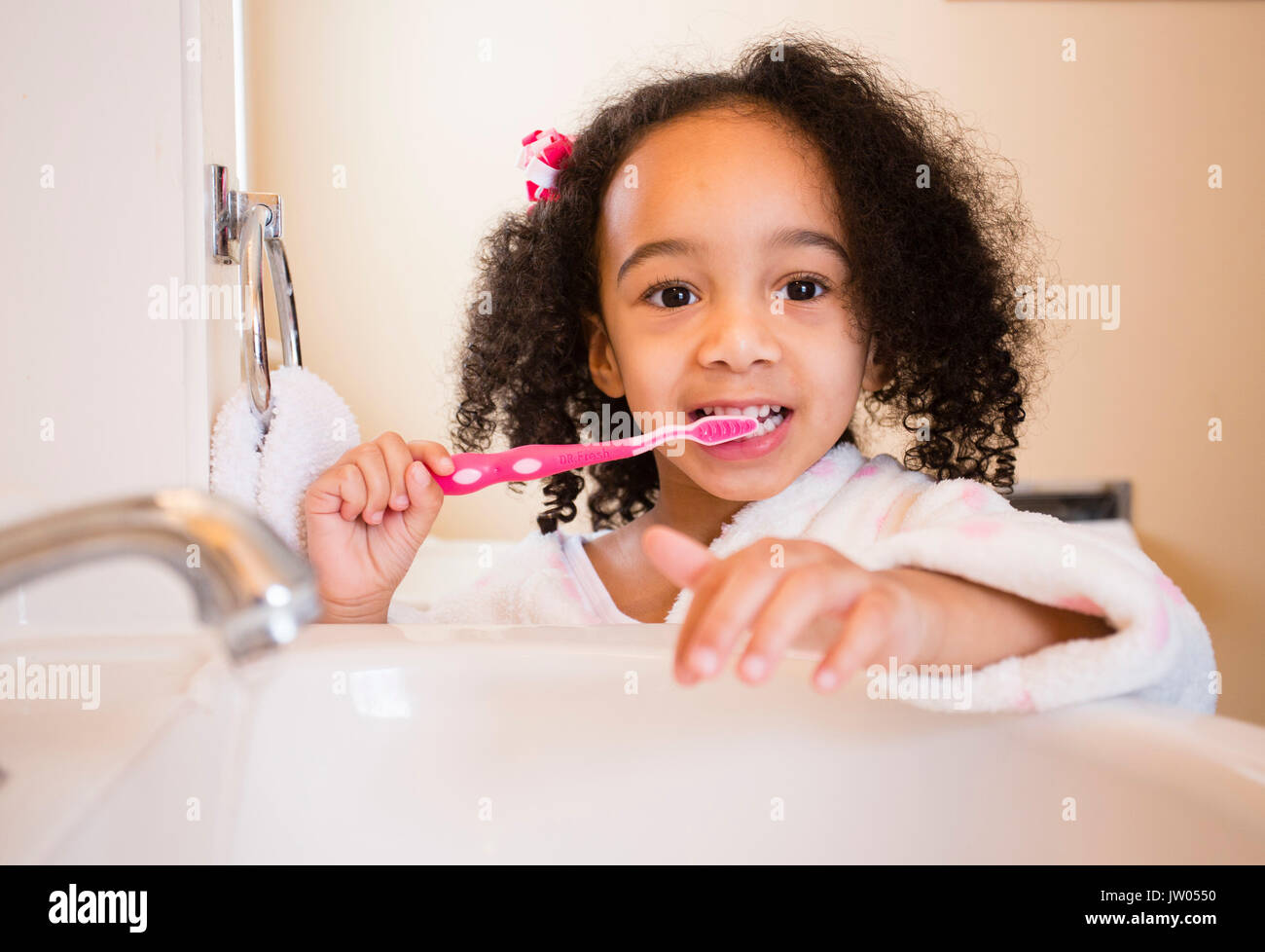 A young, multicultural girl brushes her teeth. Stock Photo