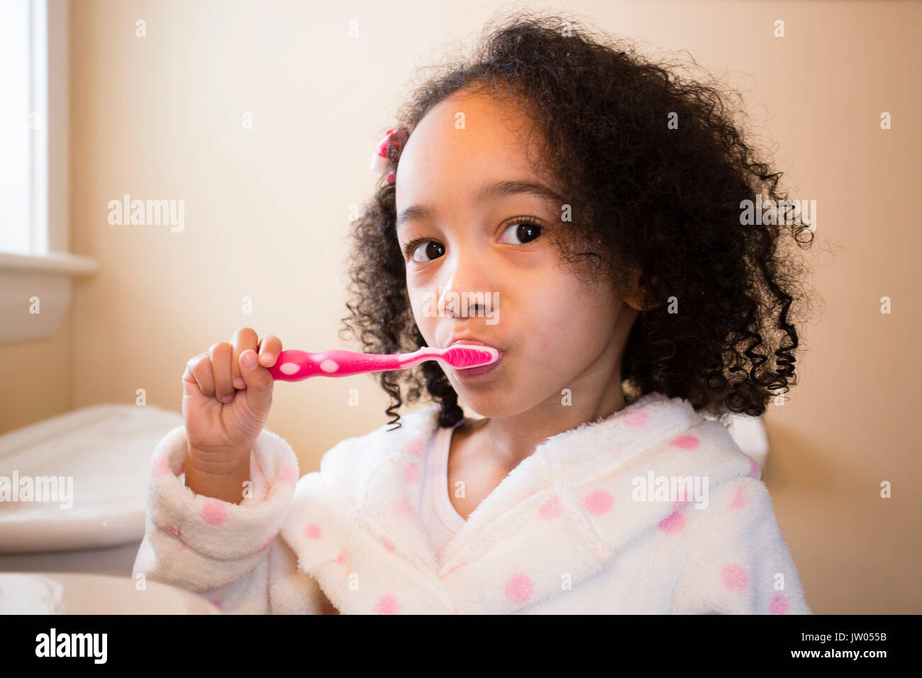 A young, multicultural girl brushes her teeth. Stock Photo