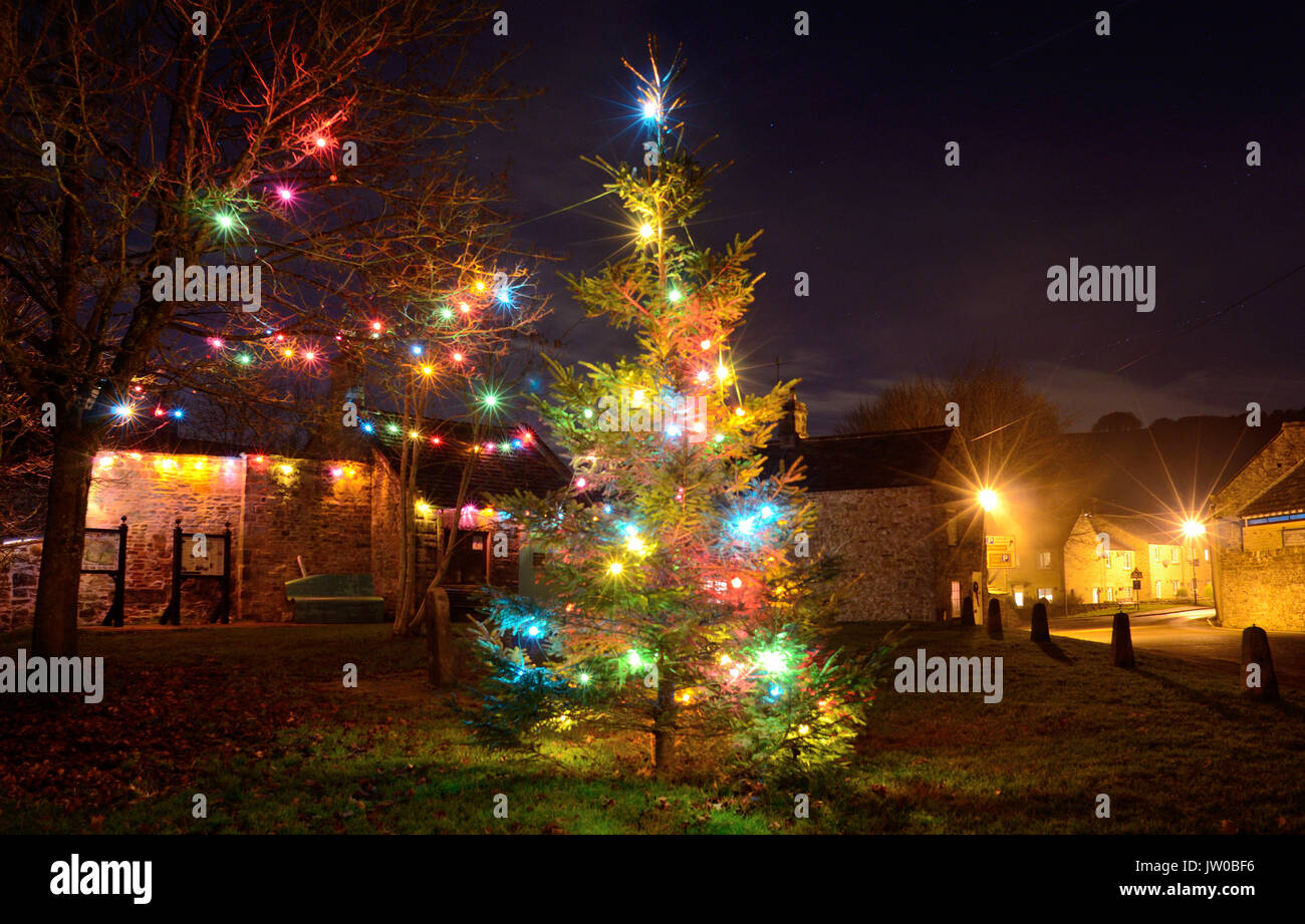 Christmas tree and festive lights embellish the village green in Eyam, an historic village in the Peak District, Derbyshire,England,UK - December Stock Photo