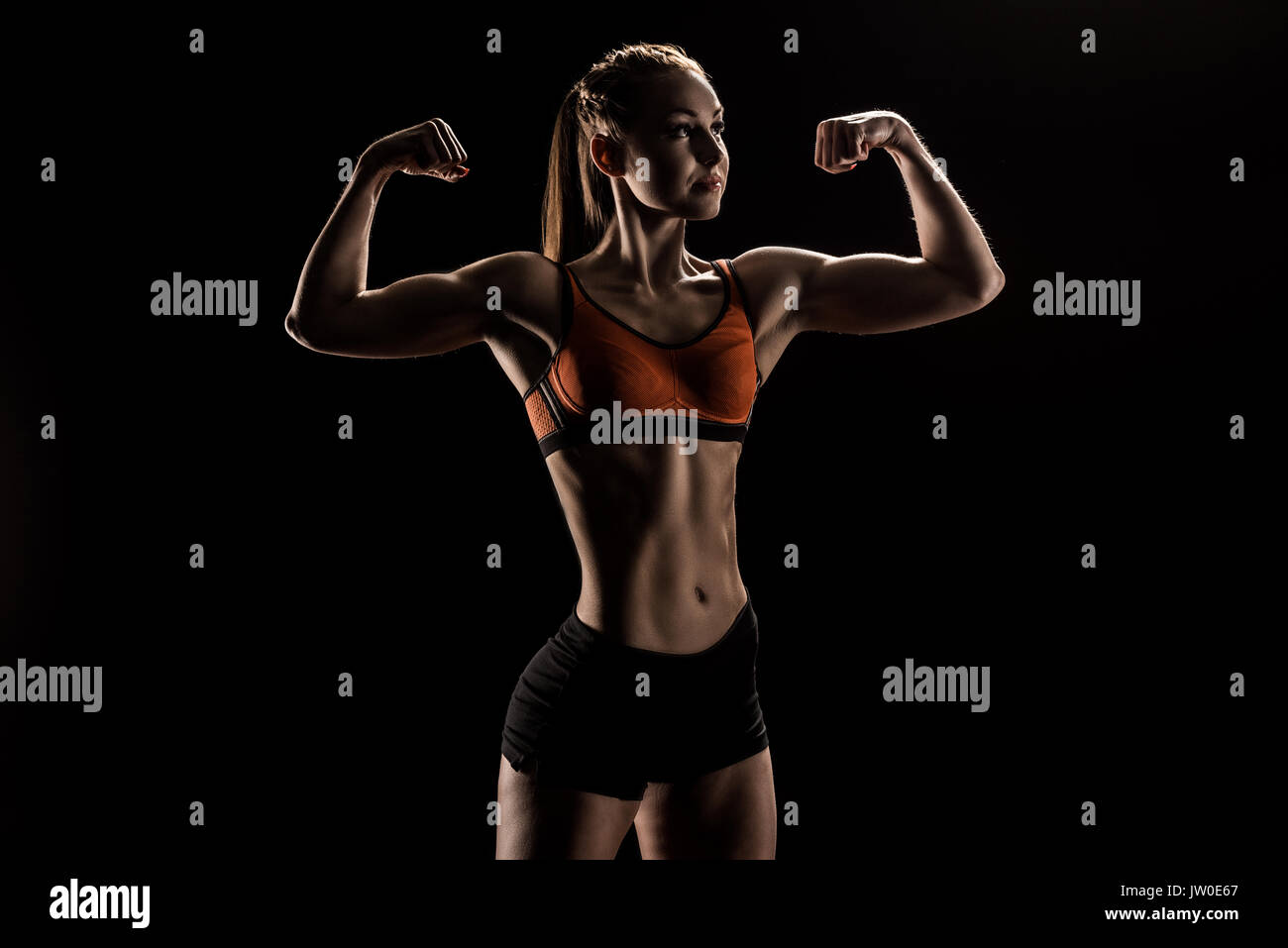 young caucasian sportswoman flexing biceps and looking away Stock Photo