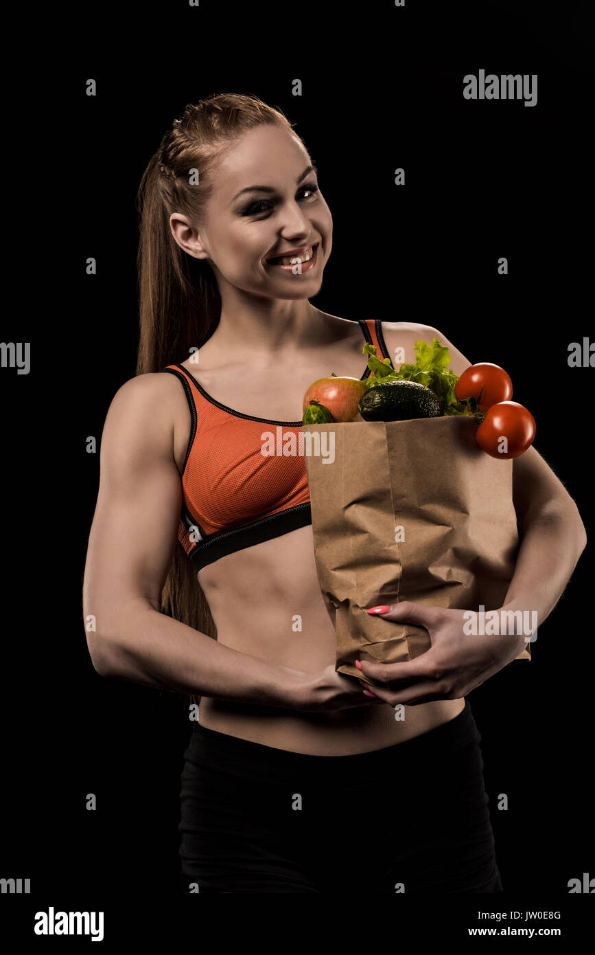 portrait of woman holding bag with vegetables and looking at camera isolated on black Stock Photo