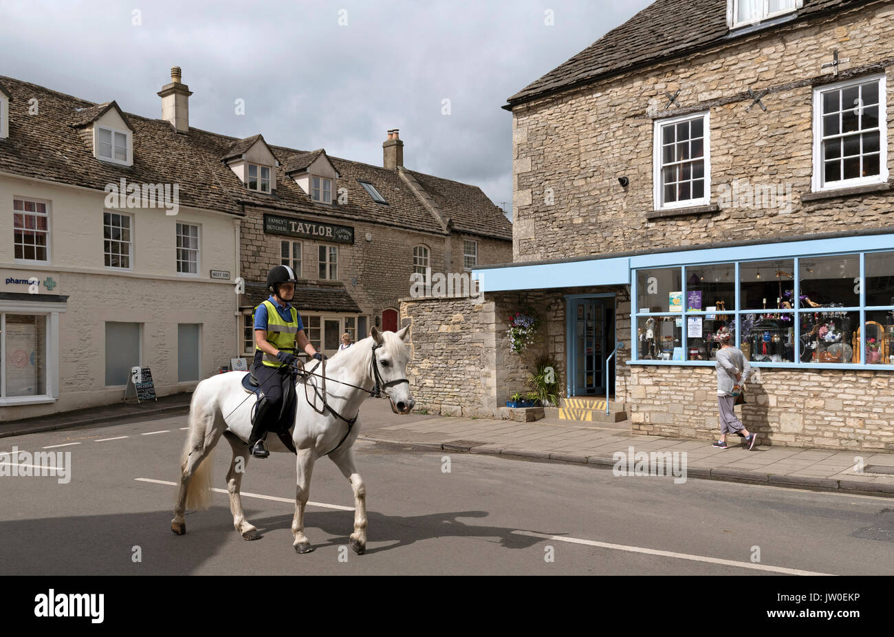 Woman on horseback passing through the Cotswold town of Minchinhampton Gloucestershire England UK Stock Photo