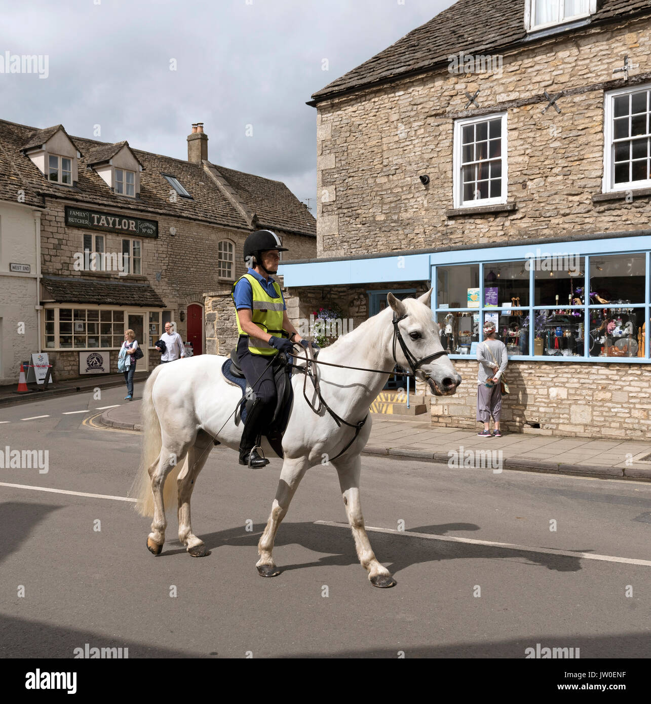 Woman on horseback passing through the Cotswold town of Minchinhampton Gloucestershire England UK Stock Photo