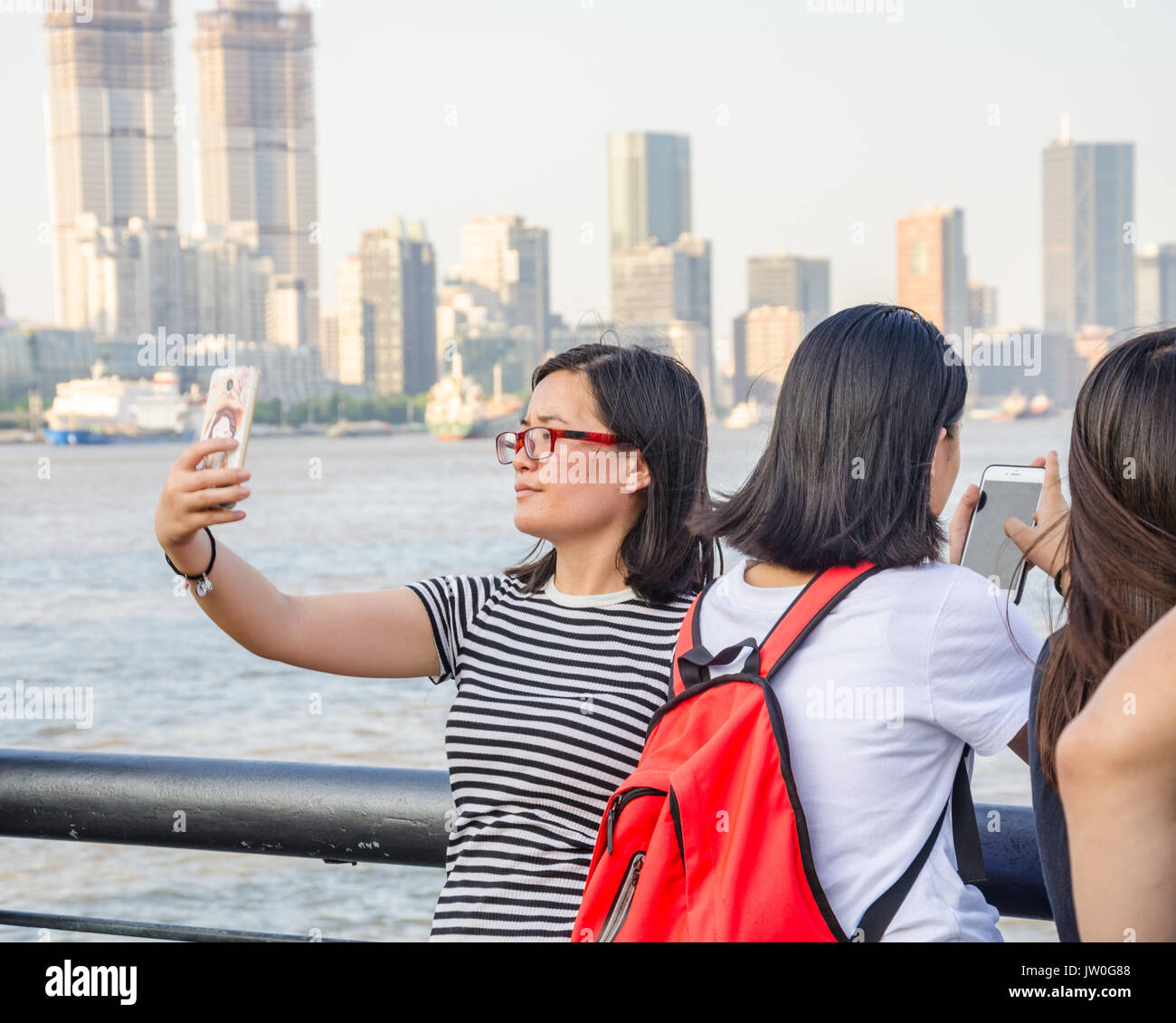 A lady takes a selfie with the Huangpu River in Shanghai, China in the background. Stock Photo