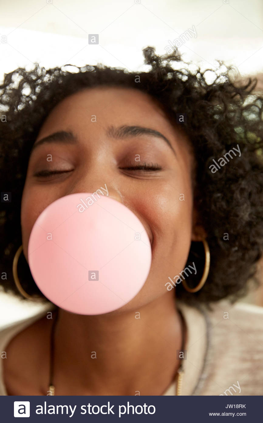 Close up playful African American woman blowing bubble with bubble gum Stock Photo