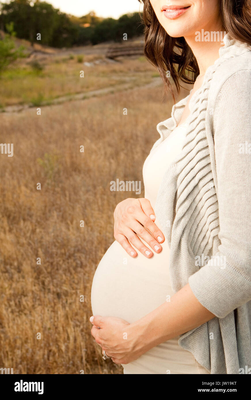 Pregnant woman ouside holding her belly Stock Photo - Alamy