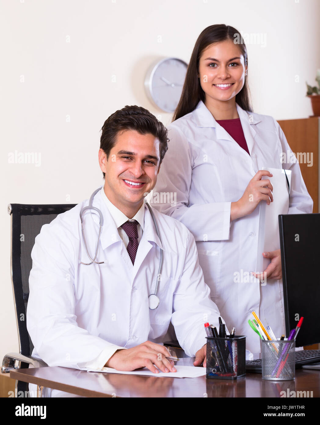 Two smiling doctors therapeutists with stethoscope posing in private clinic Stock Photo