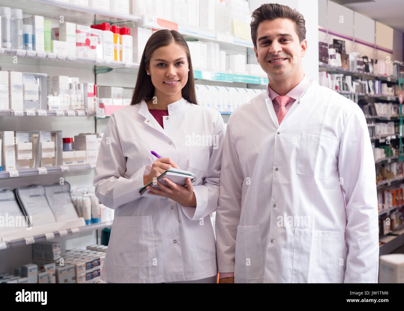 Smiling pharmacist and pharmacy assistant posing in drugstore Stock