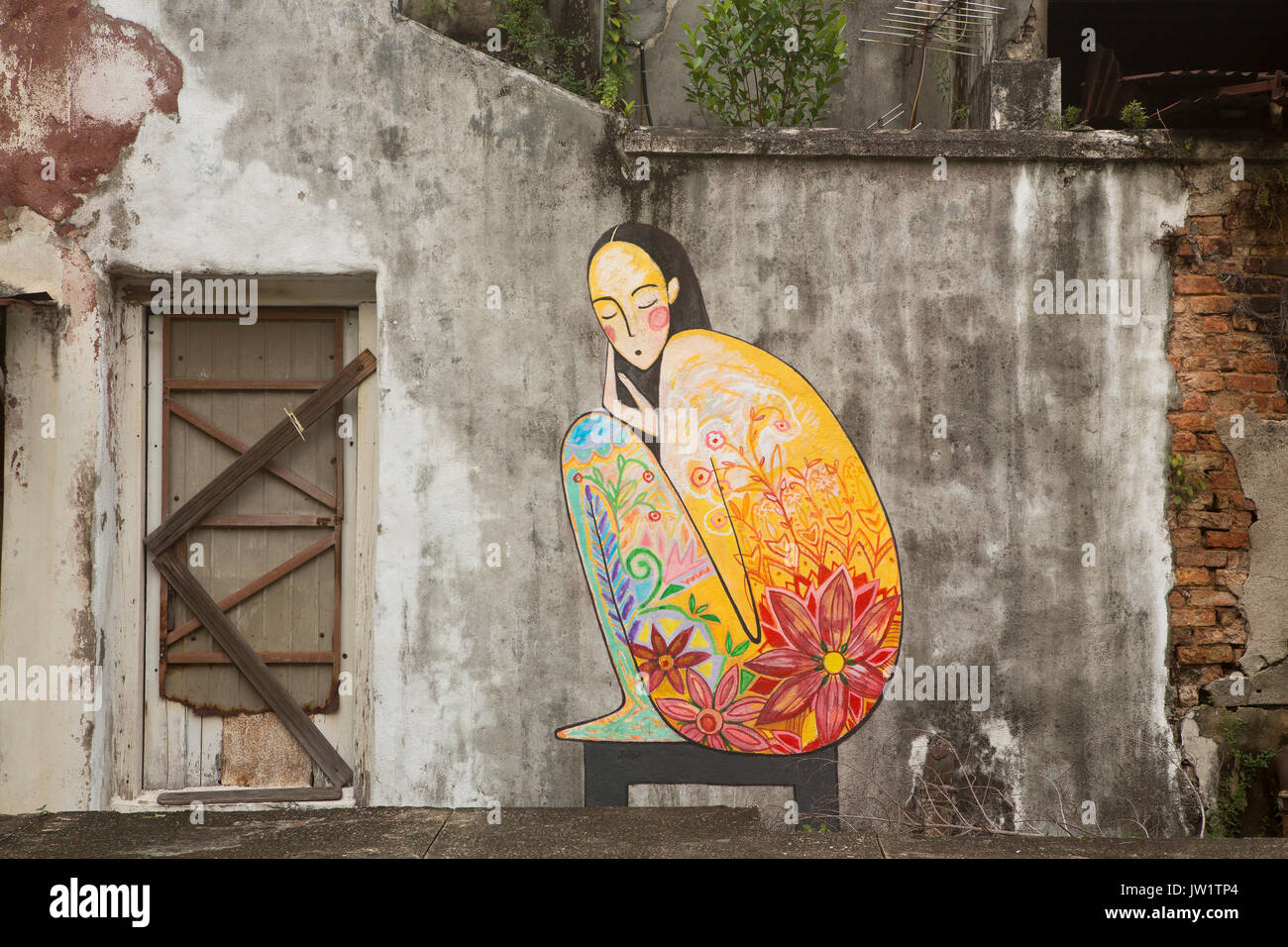 George Town Penang famous for its street art. A colourful navite girl in traditional dress adorning the wall of an old shophouse in the UNESCO area. Stock Photo