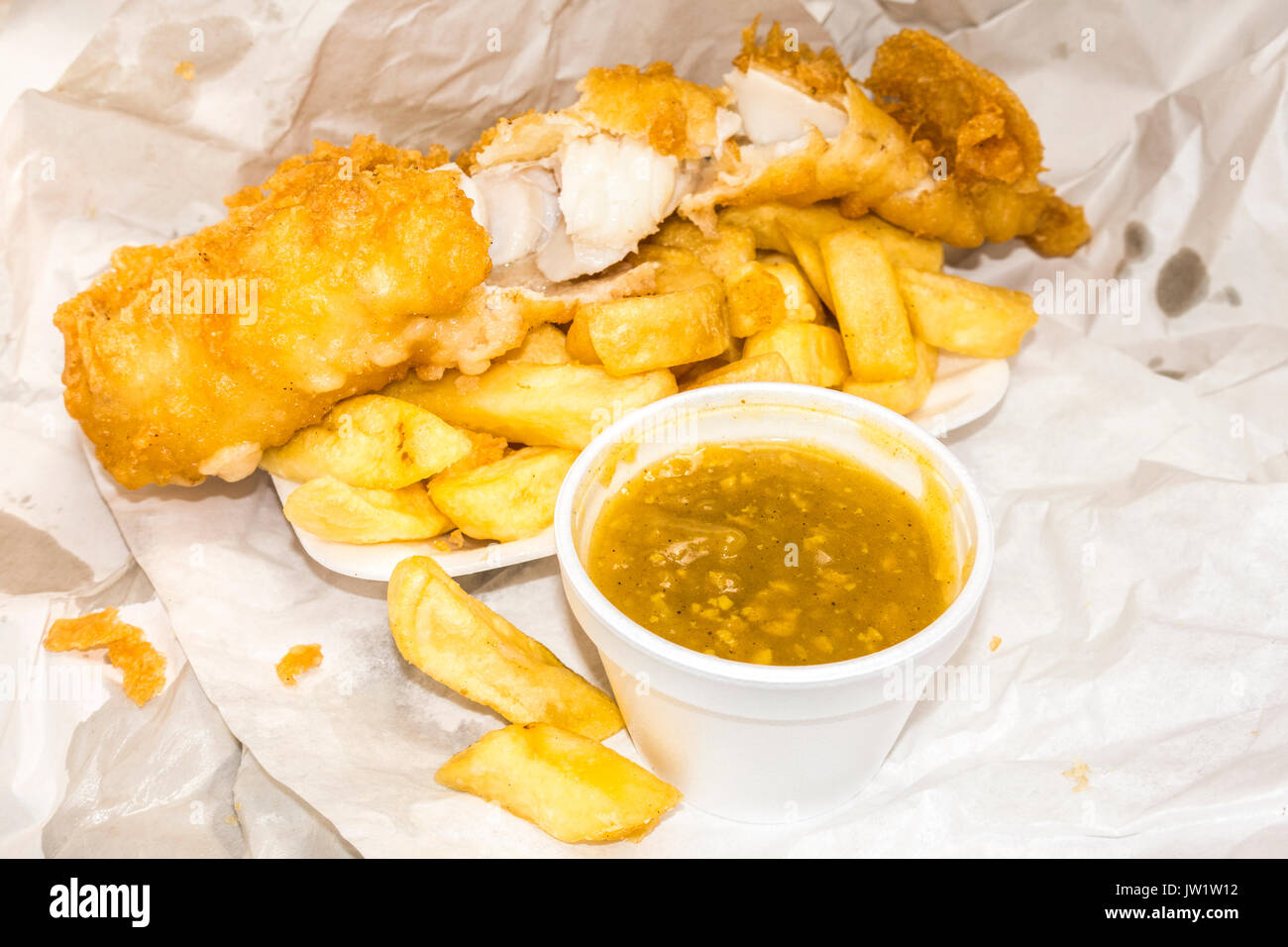 Traditional British takeaway meal of battered fish and chips, plus