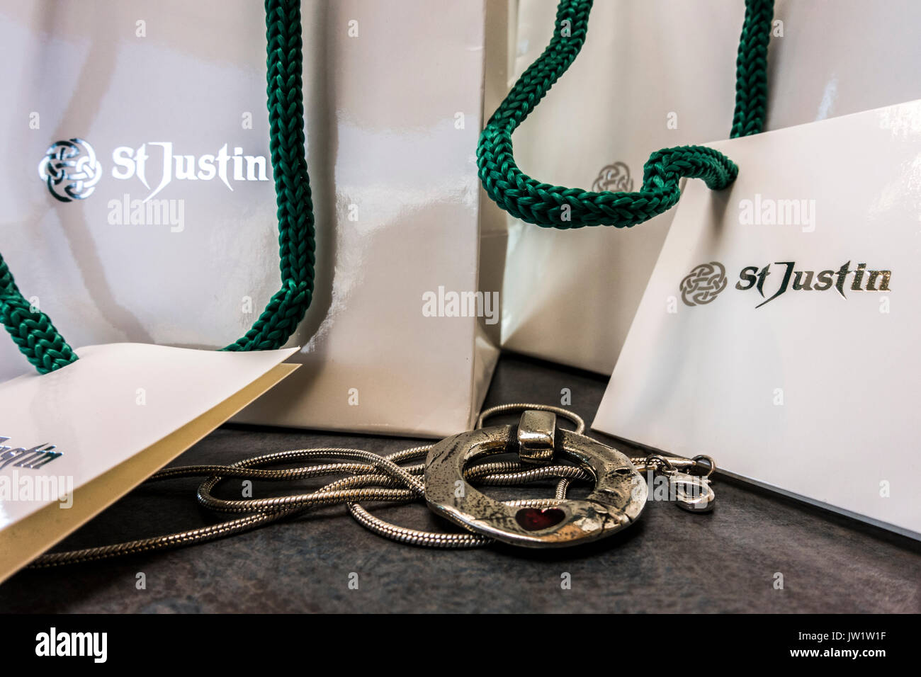 A love circle pendant hand crafted by St Justin of Penzance, Cornwall, England, UK, alongside the shop's presentation bags. Stock Photo