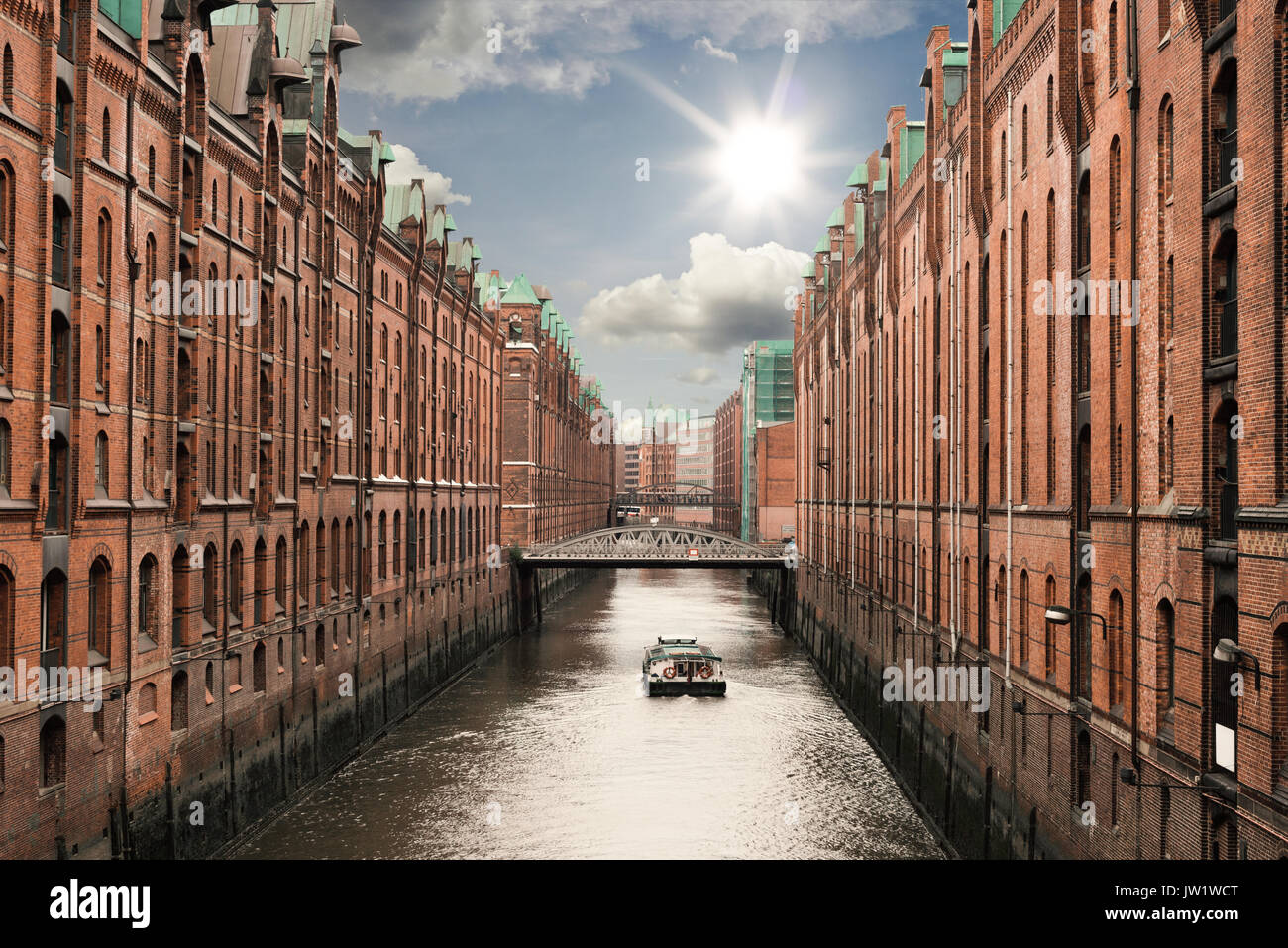 boat on a channel in the old warehouse district Speicherstadt in Hamburg, Germany under sunny blue sky Stock Photo