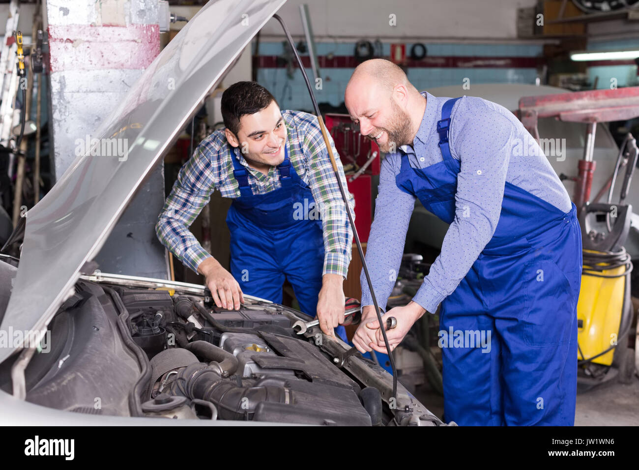 happy adult car mechanics  working at carshop Stock Photo