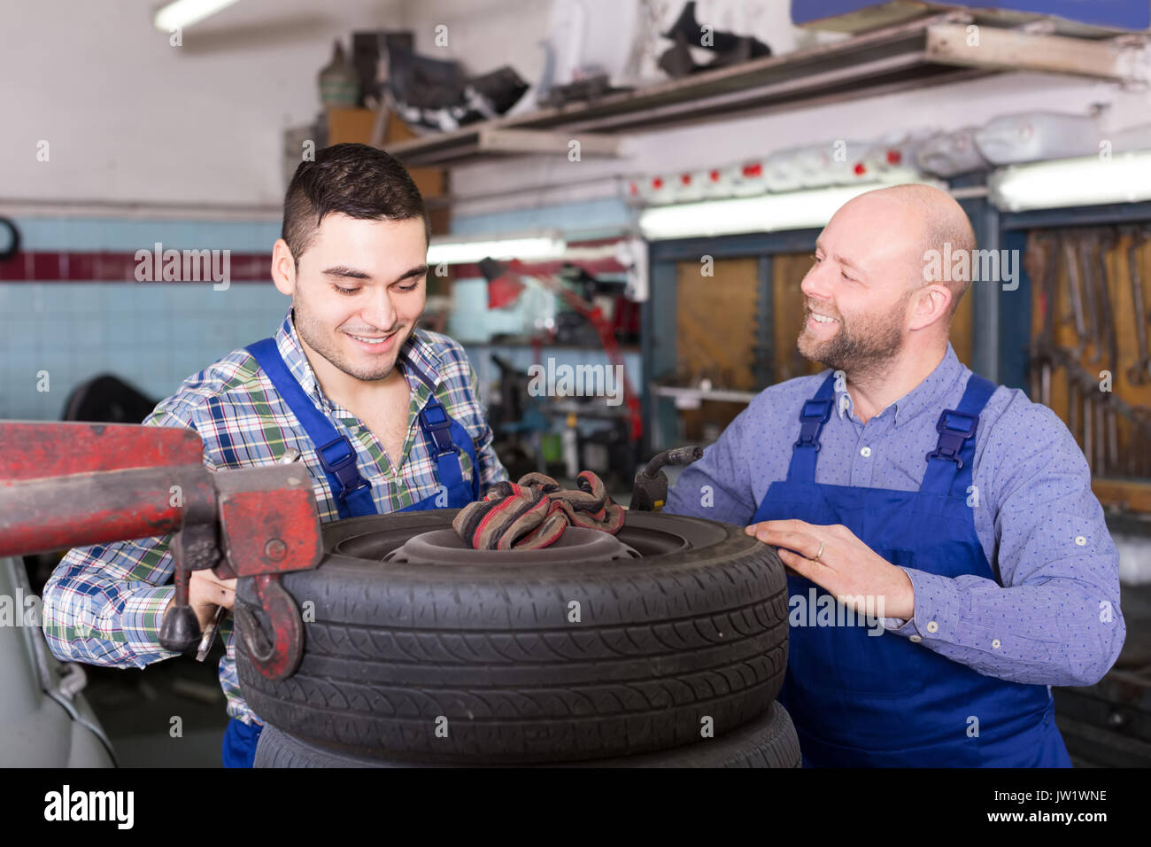 adult russian smiling car mechanics in coveralls working at carshop Stock Photo