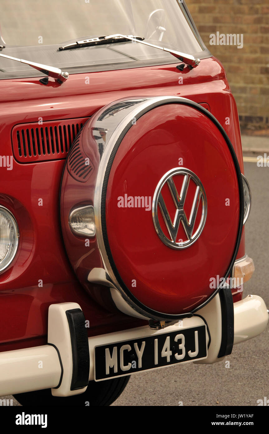 The front of an original VW camper van painted red with a designer aftermarket wheel cover on the front. Vintage air-cooled Volkswagen vans restored. Stock Photo