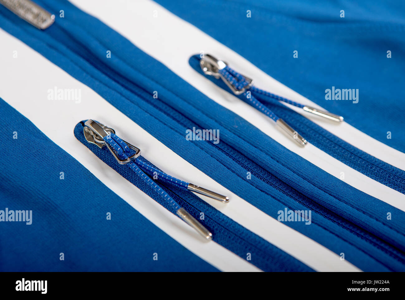 Metal zip closure sports a blue jacket or sweatshirt with pockets and white stripes close-up Stock Photo