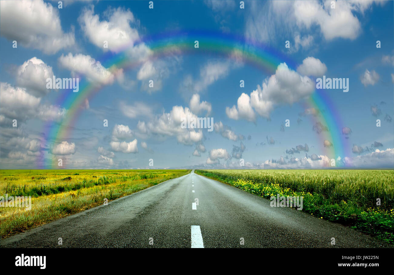 image of wide open prairie with a paved highway stretching out as far as the eye can see with beautiful small green hills under a bright blue sky in t Stock Photo