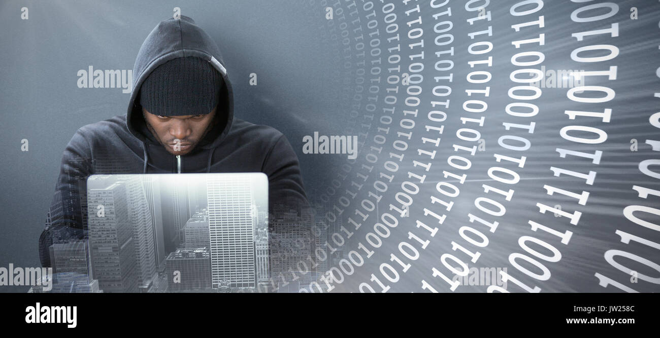 Focused male hacker using laptop  against panoramic shot binary codes on blue screen Stock Photo