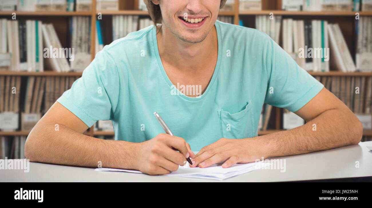 Student working against various multi colored books on shelf Stock Photo