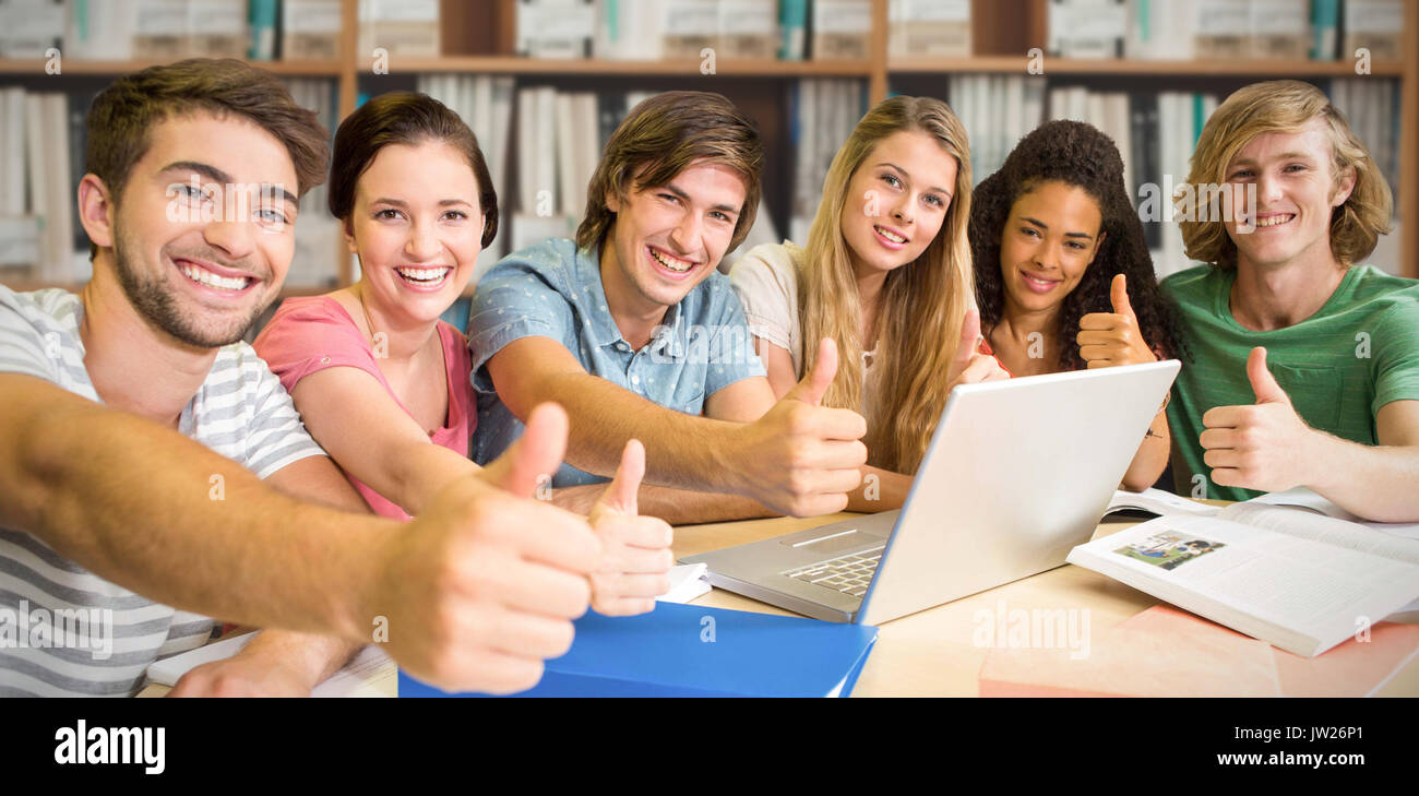 College students gesturing thumbs up in library against various multi ...
