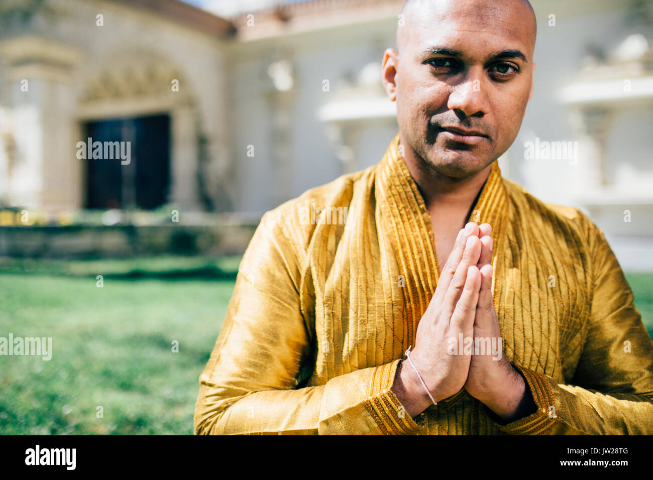 Handsom Indian Man Greeting Namaste, in Gold Kurta at the Temple Stock Photo
