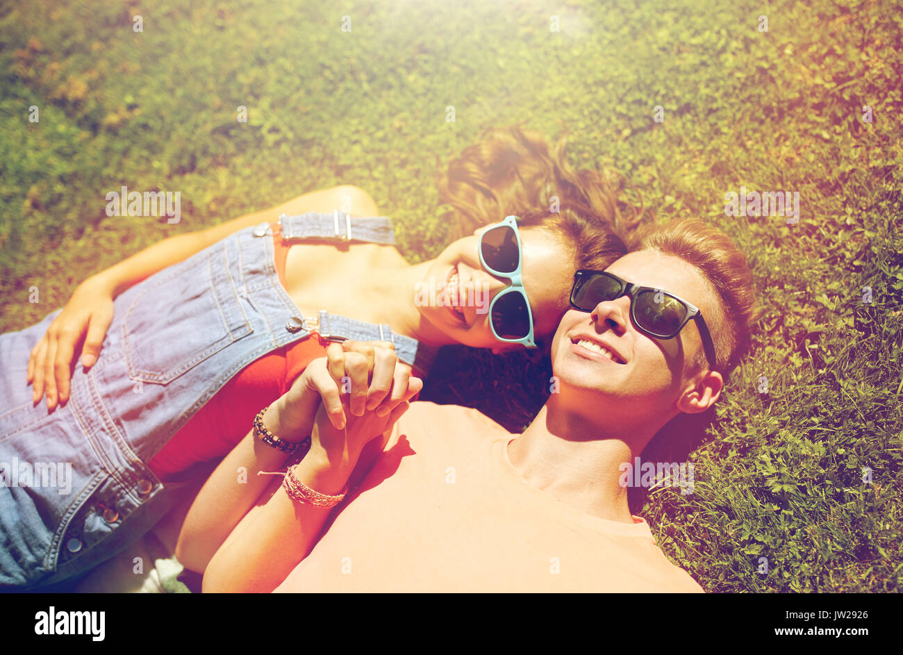 happy teenage couple lying on grass at summer Stock Photo - Alamy