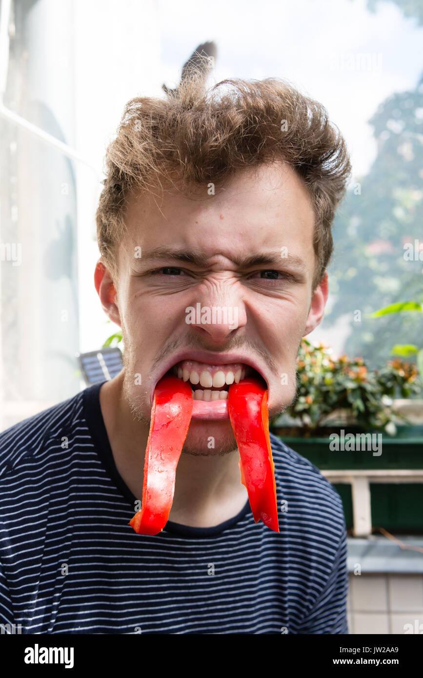 Young man looking grimly in the camera, baring his teeth, pepper vampire teeth, portrait, fun photo Stock Photo