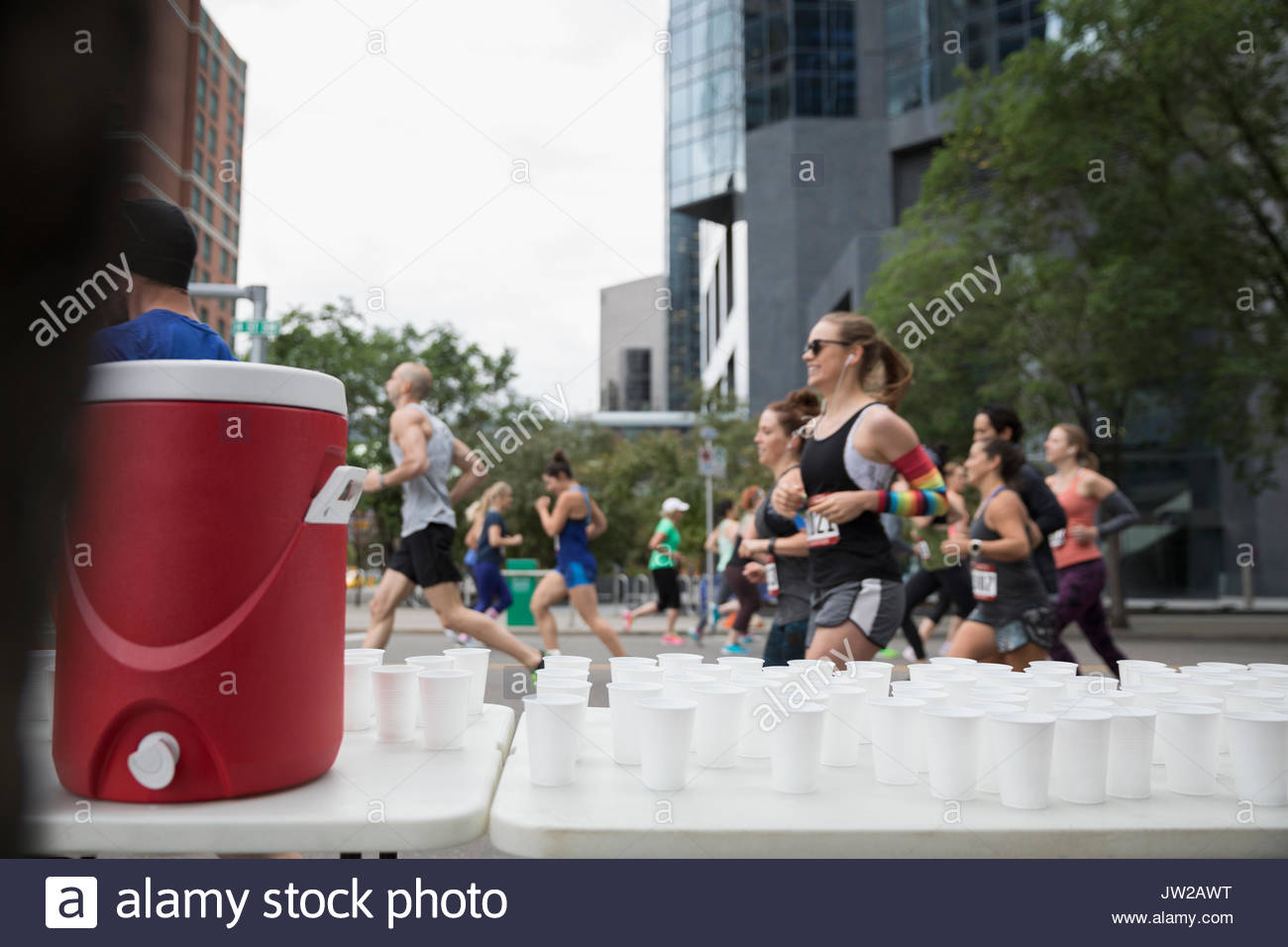 Marathon runners running, passing water station on urban street Stock Photo Alamy