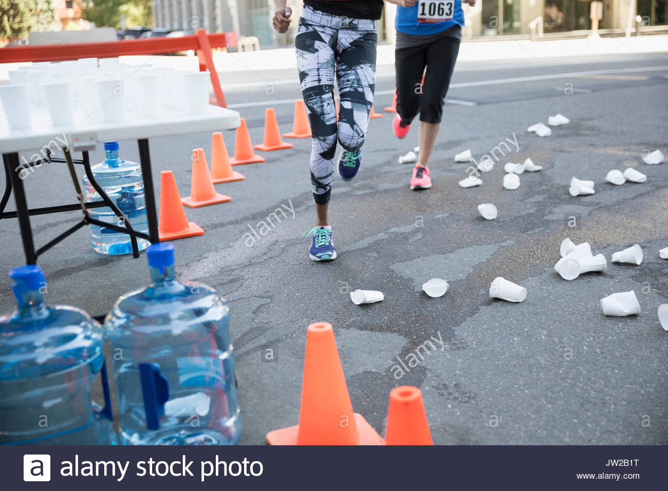 Marathon runners rounding corner with paper cups on street Stock Photo