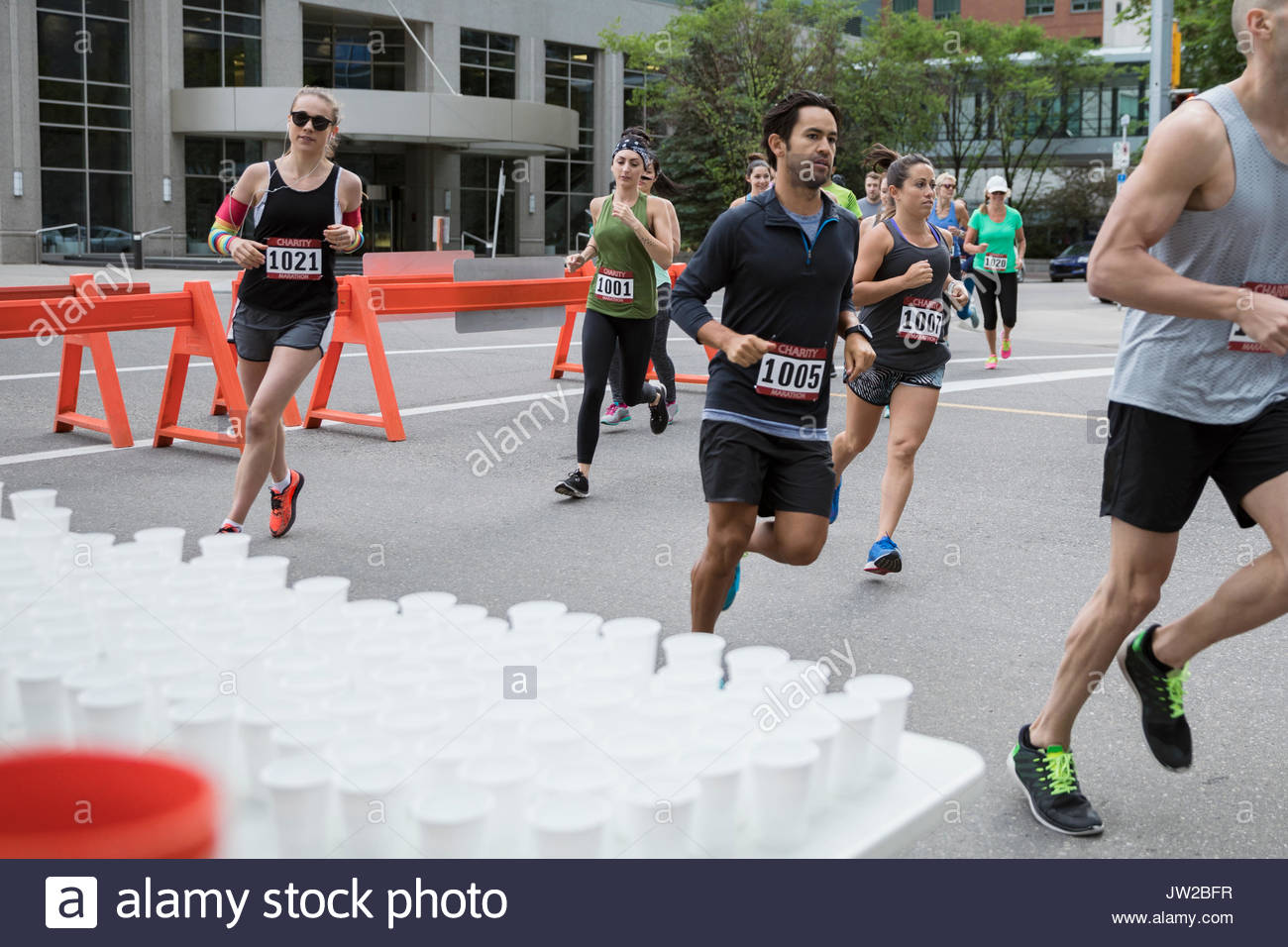 Marathon runners running, turning corner at water station on urban