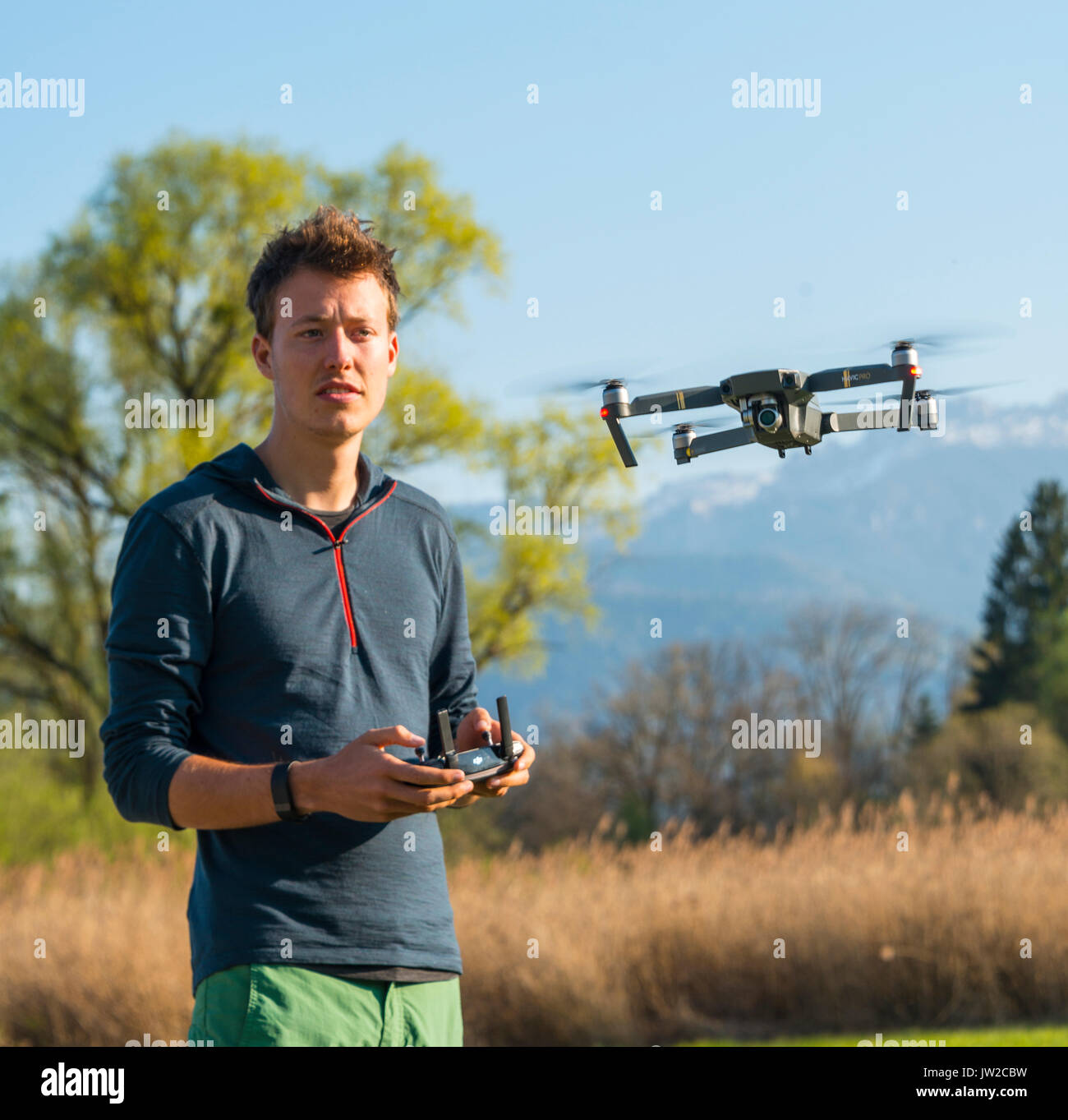 Young man controlling flying quadrocopter, remote controlled drone with camera, DJI Mavic Stock Photo