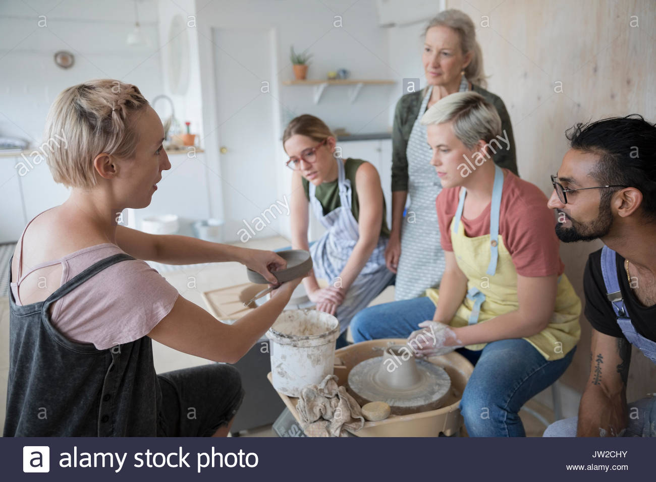 Female instructor explaining process to pottery students at pottery