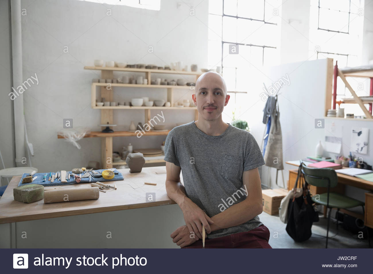 Portrait confident male potter sculpting at workbench in art studio Stock Photo