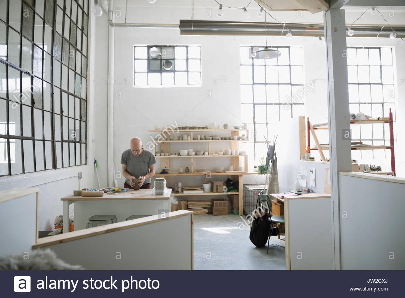 Male potter sculpting clay at workbench in art studio Stock Photo