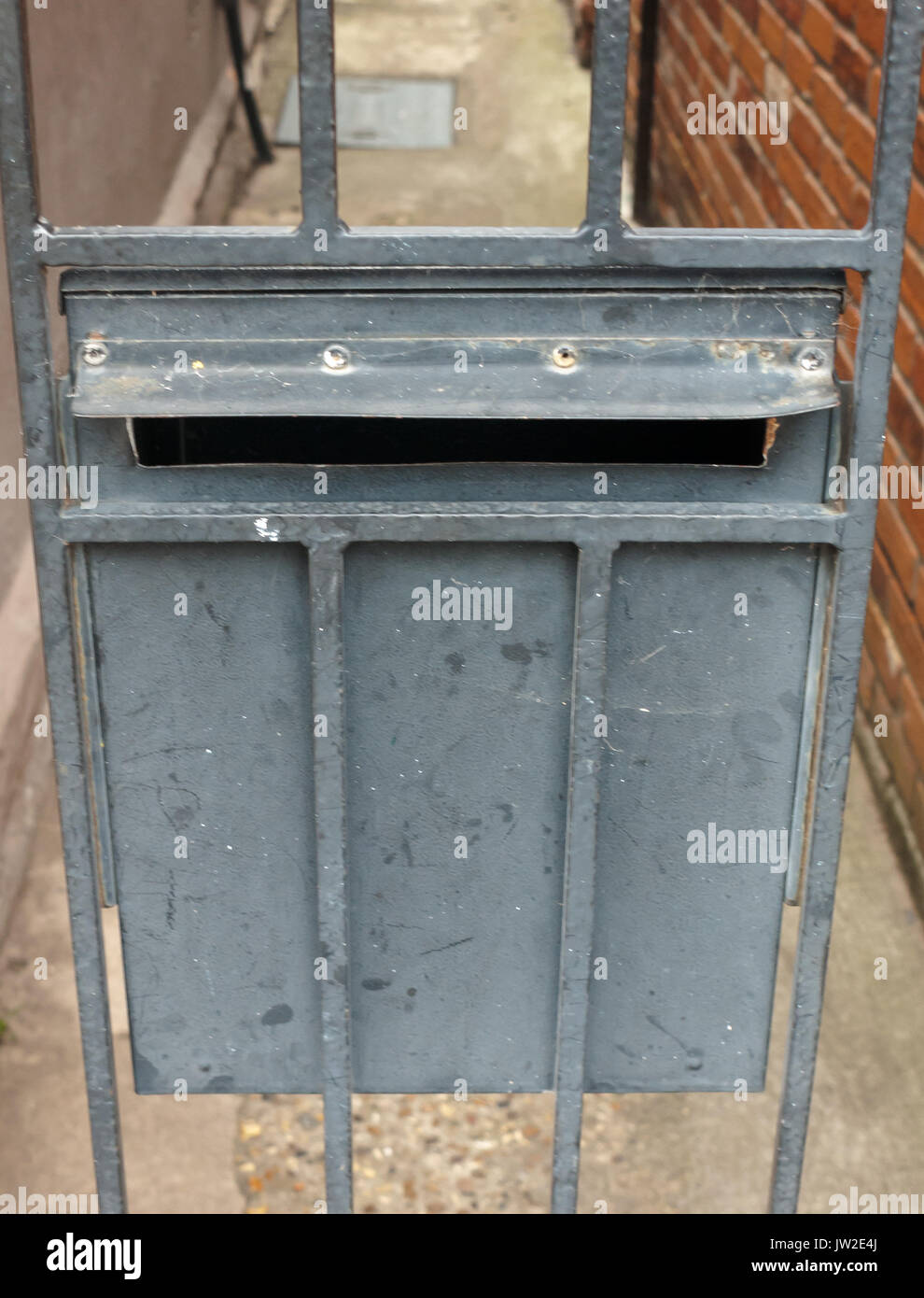 metal postbox on a gate back door rails; UK Stock Photo