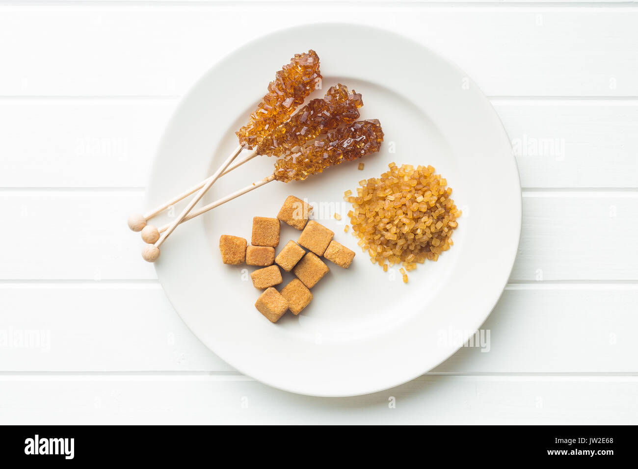 Brown cane sugar, cube sugar and crystalline sugar on plate. Top view. Stock Photo