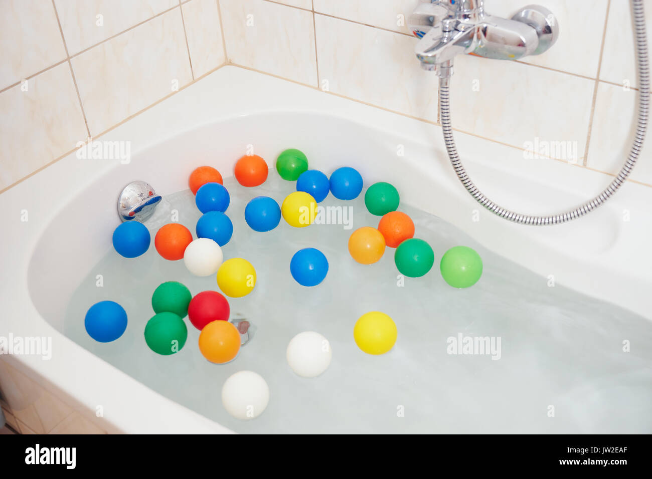 Crop shot of bathtube with water and colored ball on its surface Stock Photo