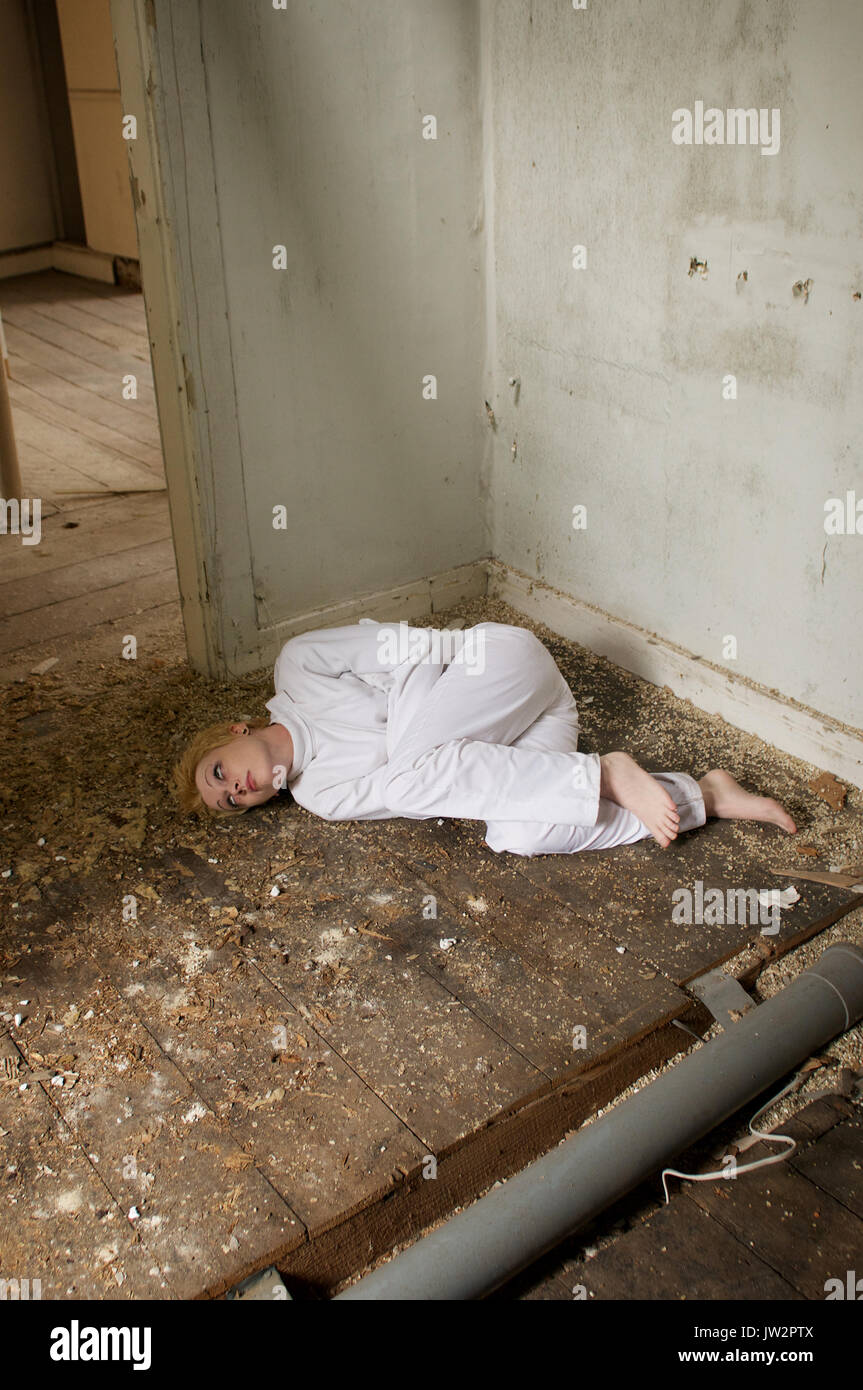 Girl in a straight-jacket inside an abandoned house Stock Photo