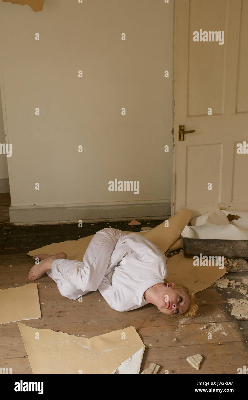 Girl in a straight-jacket inside an abandoned house Stock Photo