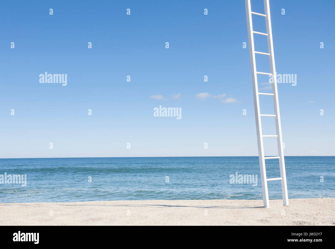 White ladder on empty beach with blue ocean in background Stock Photo