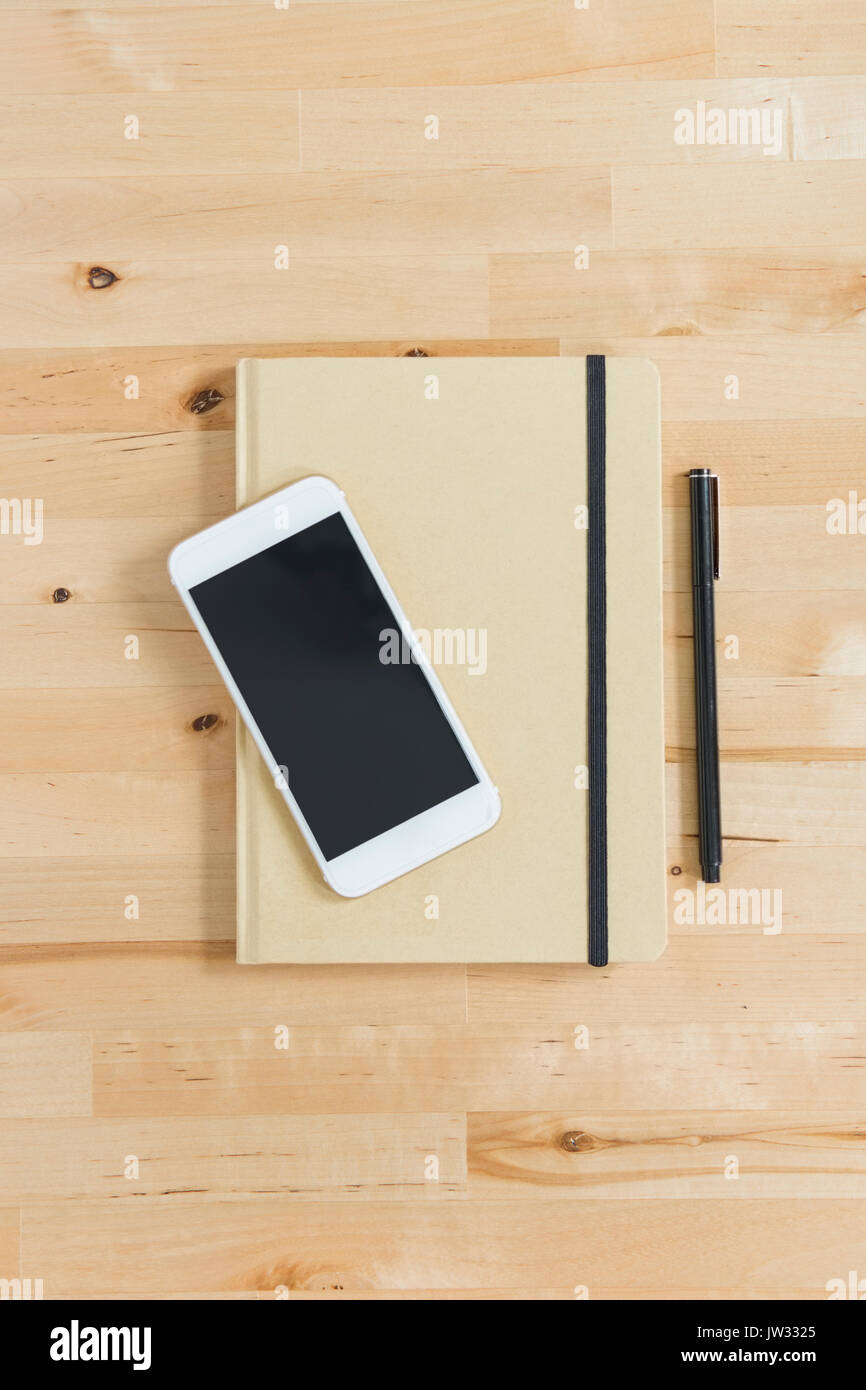 Directly above view of smart phone and personal organizer and pen on wooden desk Stock Photo