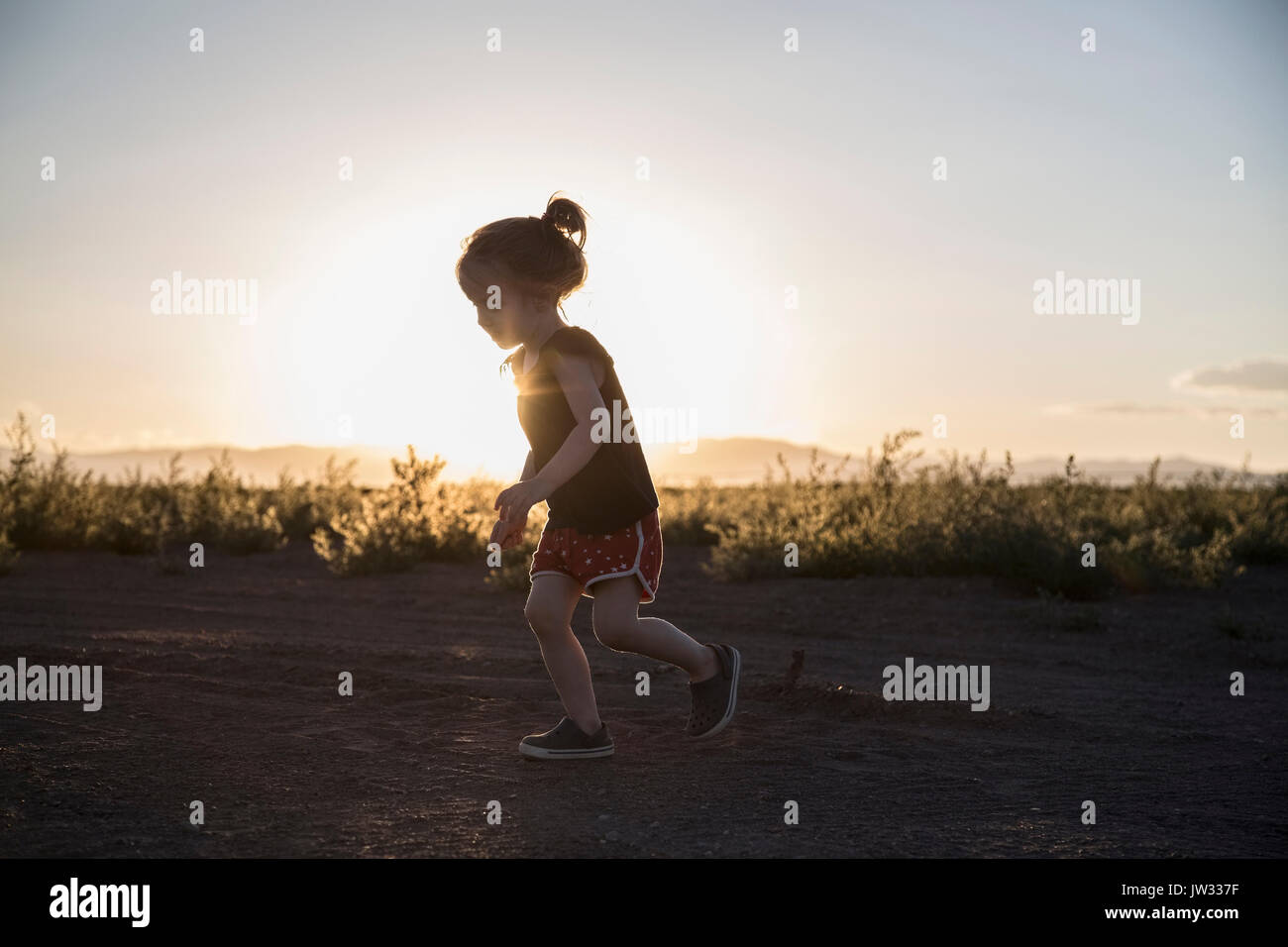 USA, Colorado, Little girl (4-5) running on dirt road at sunset Stock Photo
