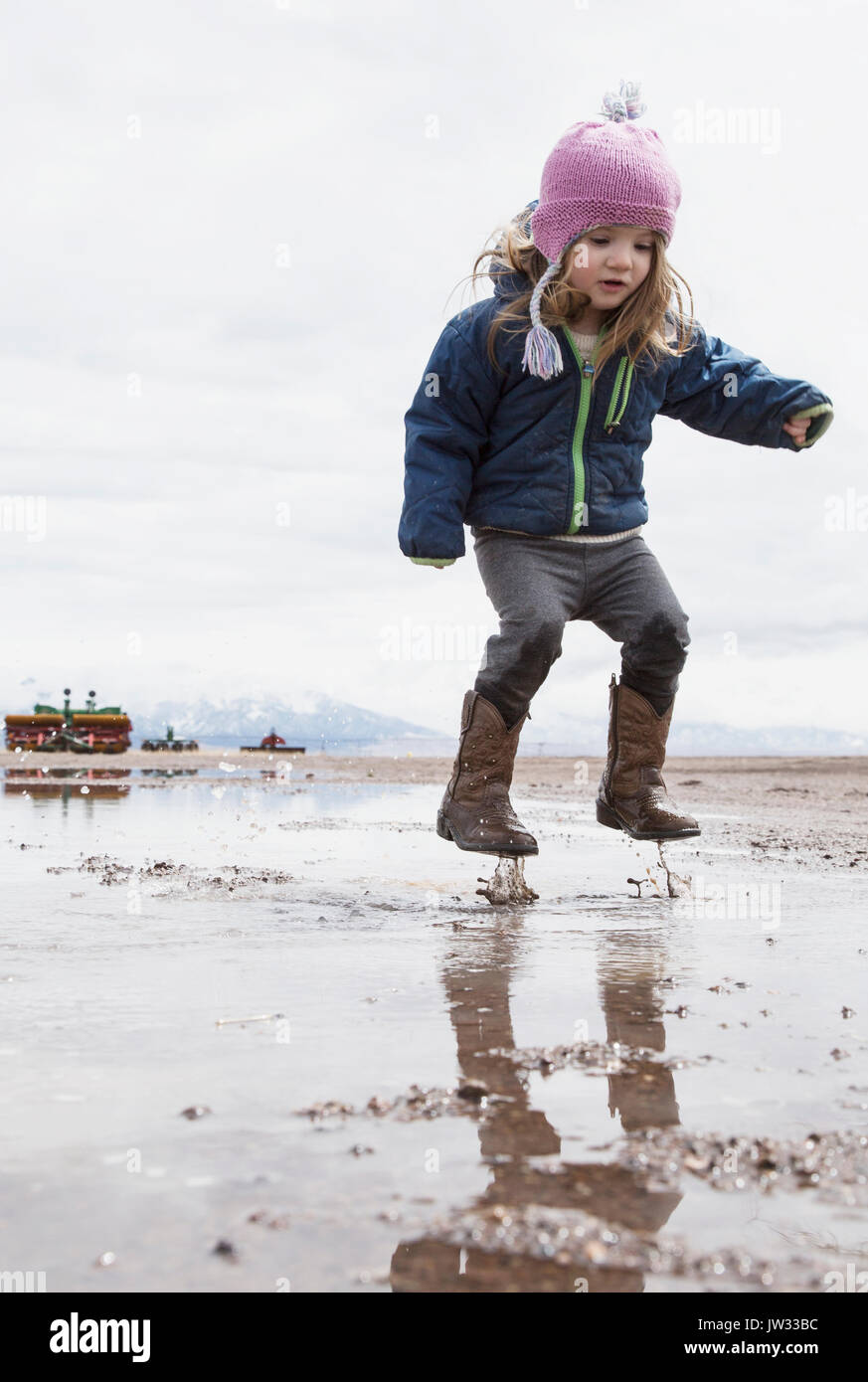 Little girl (4-5) jumping in puddle Stock Photo