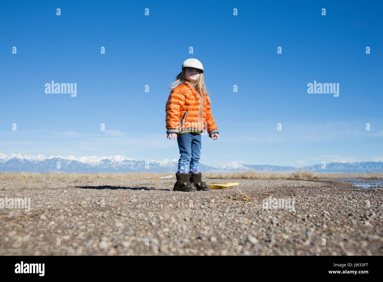 USA, Colorado, Little girl (4-5) dressed in orange padded jacket and flat cap Stock Photo